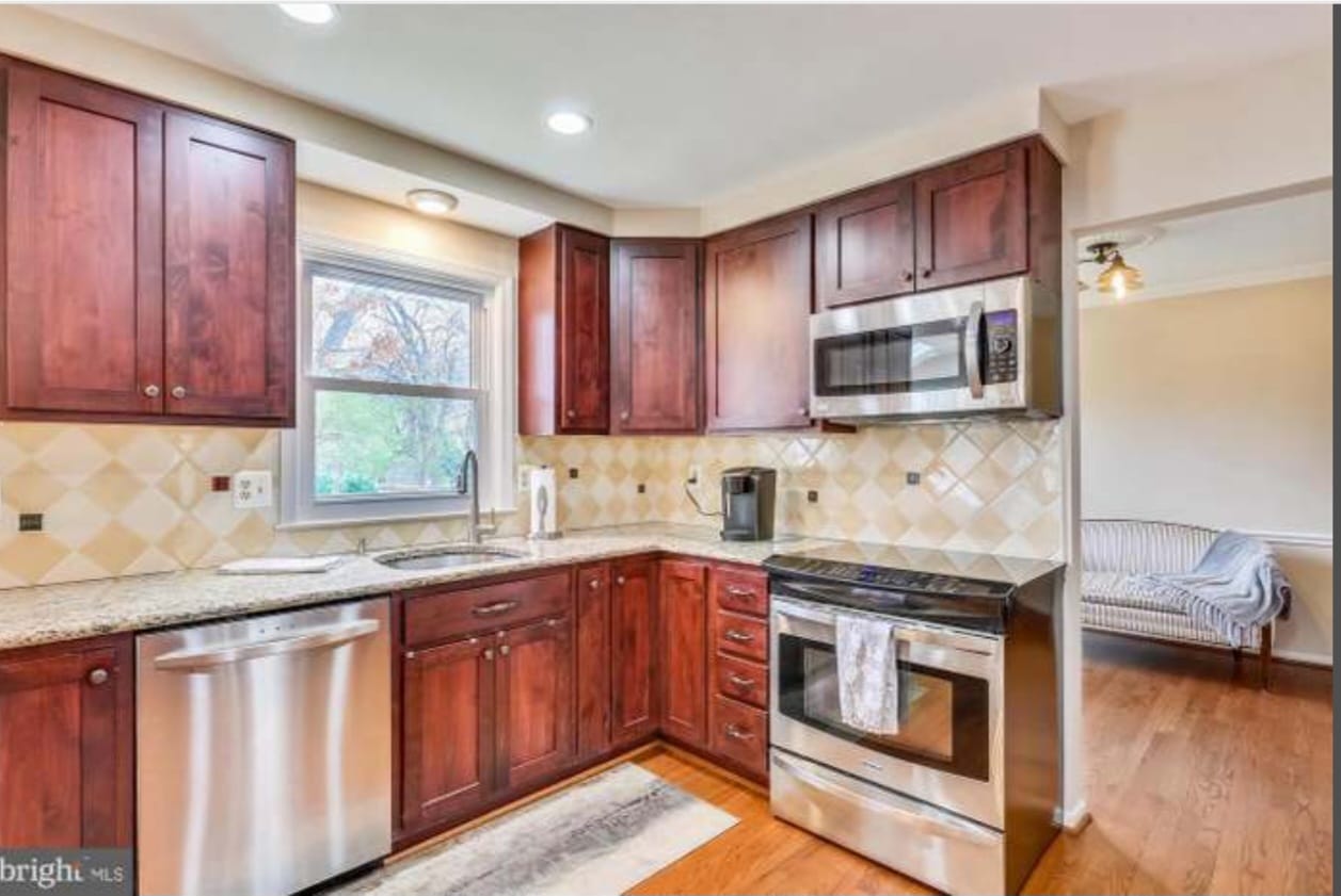 Gallery Renovated kitchen with dark wood cabinets, stainless steel appliances, and tile backsplash – Perfectum Construction & Plumbing remodeling project.
