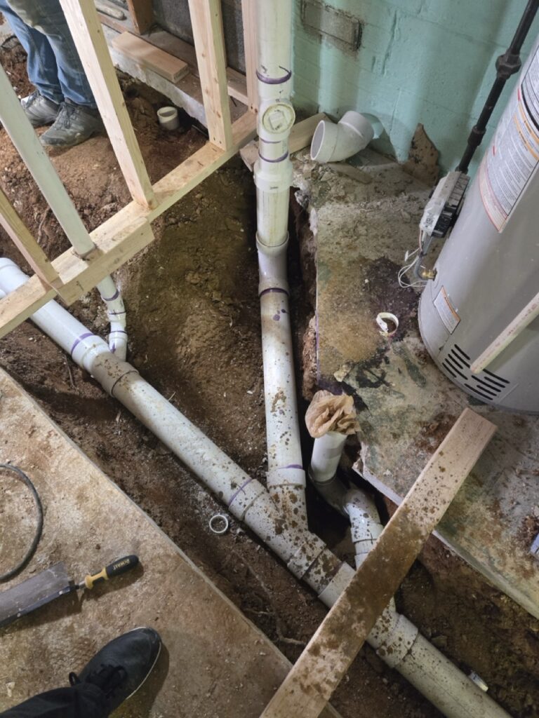 Home Basement plumbing setup with water heater and PVC drain lines by Perfectum Plumbing in Gaithersburg MD.
