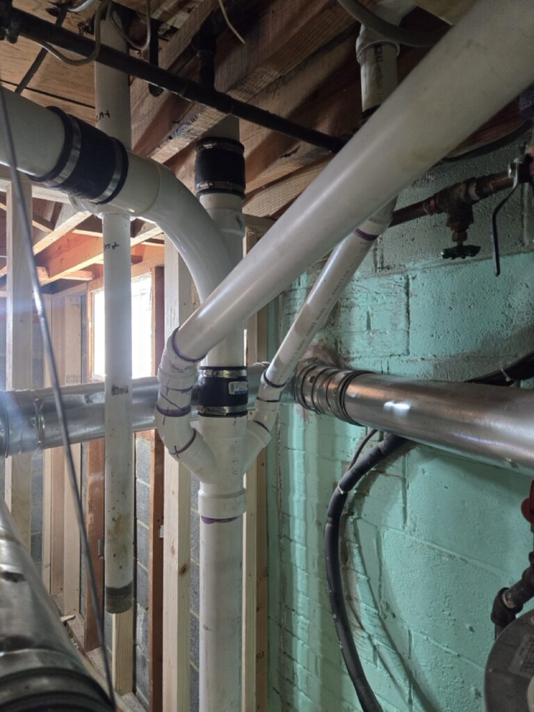 Home Messy basement plumbing with PVC drain lines and copper pipes in Gaithersburg MD.