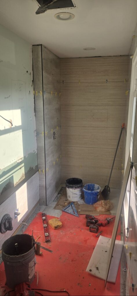 Gallery Bathroom remodeling project in progress featuring tiled shower walls and construction tools.