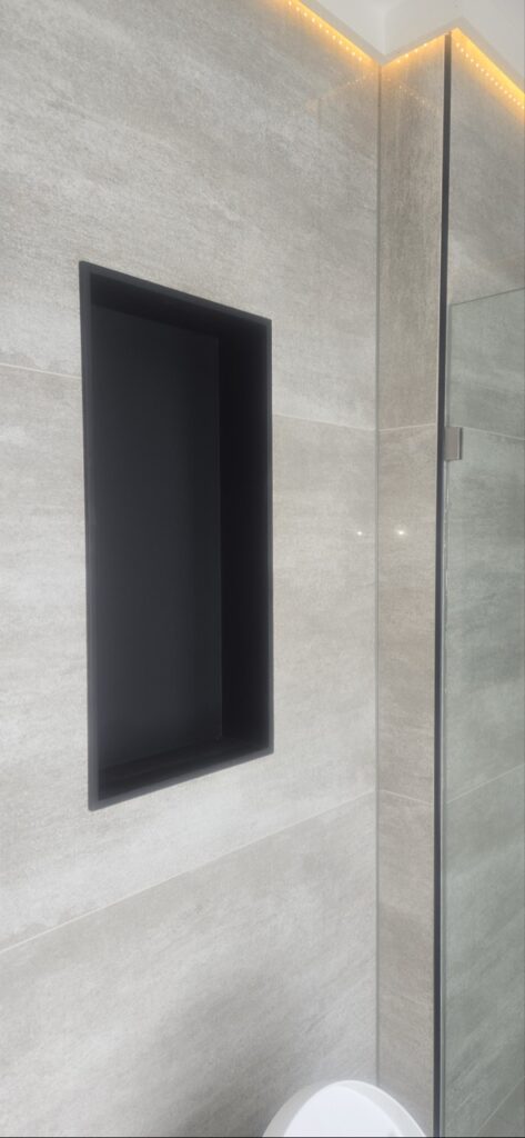 Gallery Stylish bathroom remodel with gray tile and recessed niche by Perfectum Construction & Plumbing.