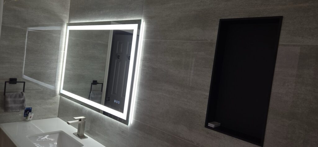 Gallery Modern bathroom remodel with illuminated mirror and vanity by Perfectum Construction & Plumbing.