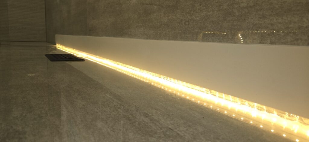 Gallery Stylish bathroom remodel with illuminated vanity and tile work by Perfectum Construction & Plumbing.