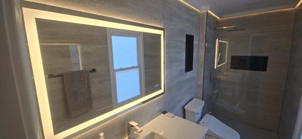 Gallery Modern bathroom remodel with lighted mirror and glass shower enclosure by Perfectum Construction & Plumbing.