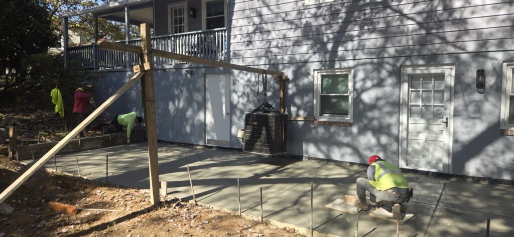 Gallery House remodeling and restoration project in Gaithersburg, MD, featuring Perfectum Construction and Plumbing workers installing concrete patio.