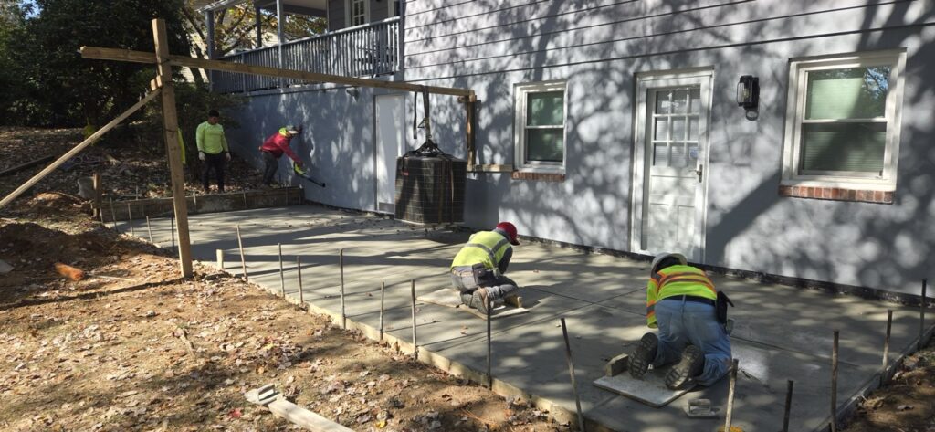Gallery Perfectum Construction & Plumbing: Gaithersburg, MD house remodeling and restoration project with workers installing concrete patio.