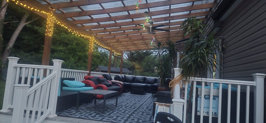 Gallery Wooden pergola with string lights and outdoor seating area, showcasing Perfectum Construction & Plumbing remodeling project.