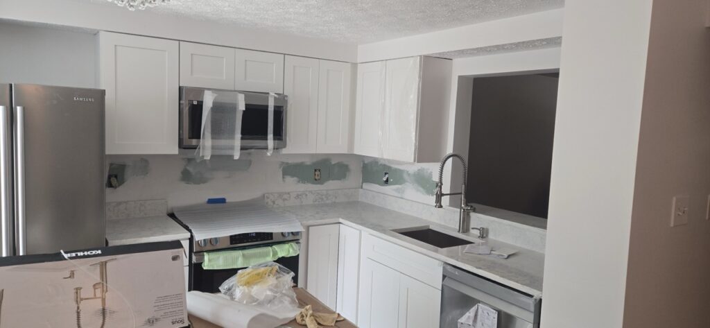 Gallery Newly remodeled kitchen with white cabinets, stainless steel appliances, and modern fixtures by Perfectum Construction & Plumbing.