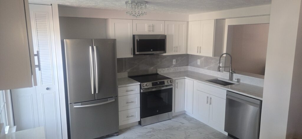 Gallery Completed kitchen remodel with white cabinetry and stainless steel appliances by Perfectum Construction & Plumbing.