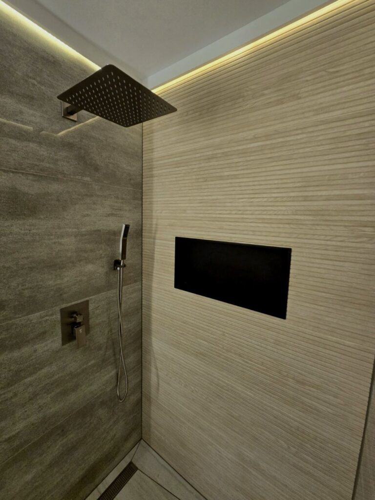 Gallery Modern bathroom remodel with rainfall showerhead and tiled shower niche by Perfectum Construction & Plumbing.