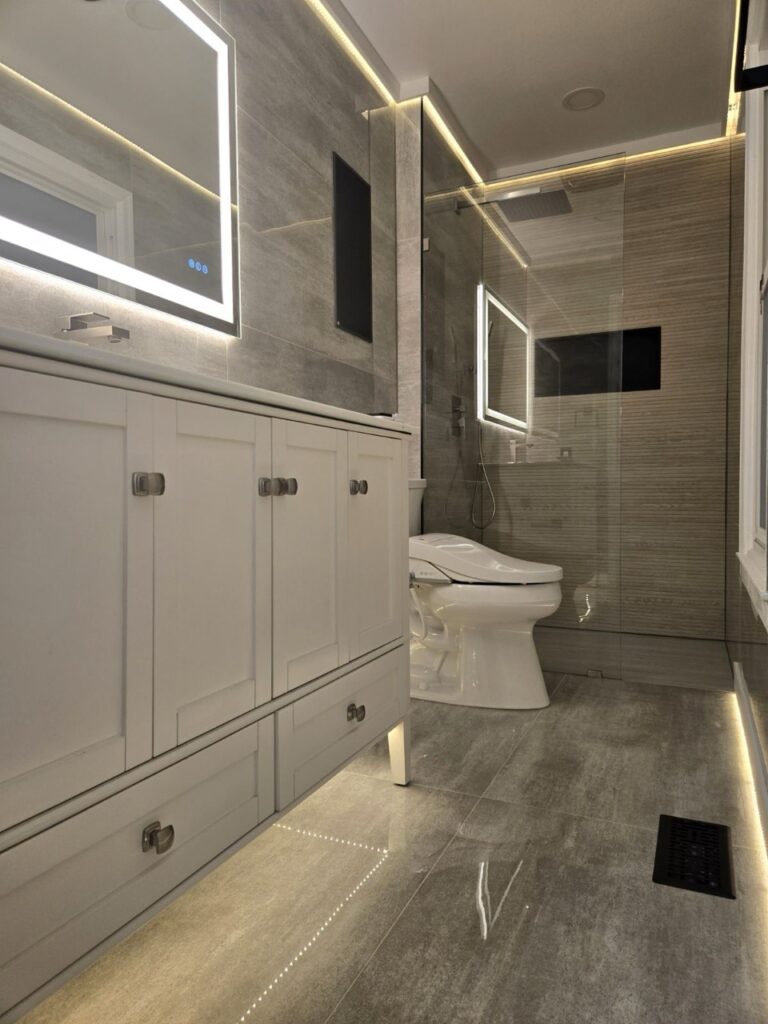Gallery Modern bathroom remodel with gray tile and white vanity by Perfectum Construction & Plumbing.