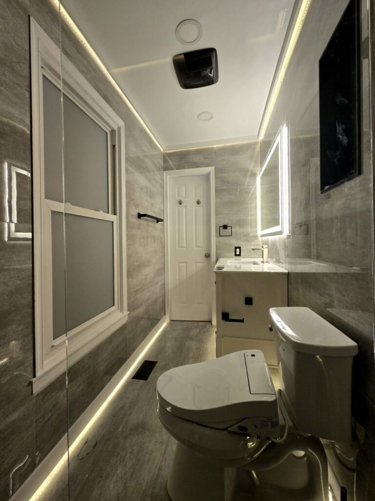 Gallery Newly remodeled bathroom with modern lighting and fixtures by Perfectum Construction & Plumbing.